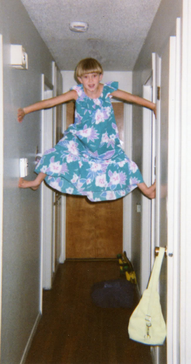 Holly in a little-girl muumuu climbing up the walls in the hallway