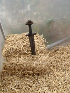 a sword stuck in a haybale