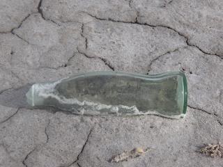 old coke bottle lying on cracked earth