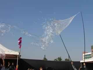 bubbles blown by wind from a net between two long poles, in India