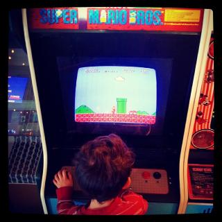 young child playing full-size arcade Super Mario Brothers