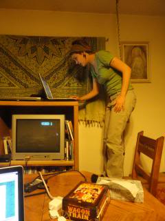 Holly, teen, standing on a chair, using her laptop on top of a TV cabinet