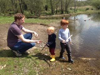 dad and two little boys playing by a lake