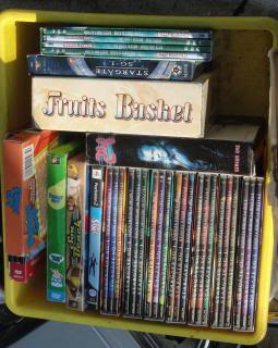 crate of videos and DVDs at a garage sale, with the Japanese anime series 'Fruits Basket' prominently shown